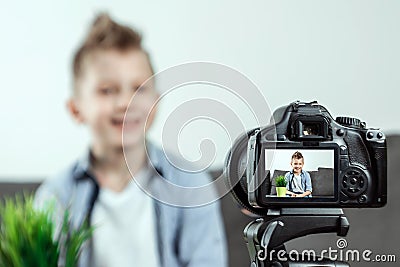 The boy is sitting in front of a SLR camera, close-up. Blogger, blogging, technology, earnings on the Internet. copy space Stock Photo