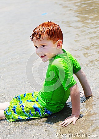 Boy sitting in shallow water Stock Photo