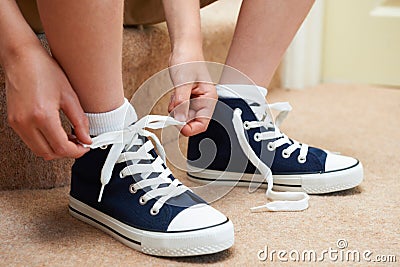 Boy Sitting On Stairs Tying Shoelaces Stock Photo