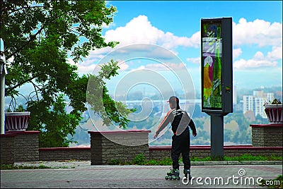 The boy skates on roller-skaters down the street in spring Editorial Stock Photo