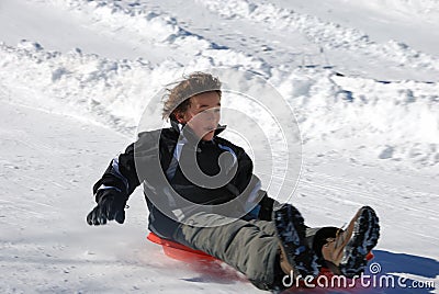 Boy Sledding Fast Down the Hill on a Red Sled Stock Photo