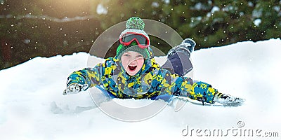 Boy sledding in a snowy forest. Outdoor winter fun for Christmas vacation. Stock Photo