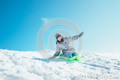 Boy slides down from the snow slope. Enjoying the winter sledding time Stock Photo