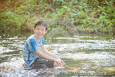 Boy smiling while palying in the river Stock Photo