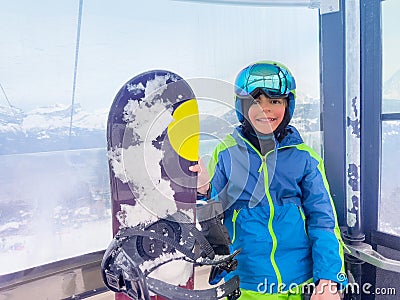 Boy with snowboard in the cabin of a chairlift holding board Stock Photo