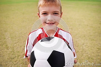 Boy, soccer player and ball with portrait, smile and ready for game, field and child. Outdoor, playful and sport for Stock Photo