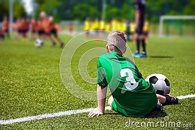 Boy soccer player on sports field. Child sitting on football grass field Editorial Stock Photo