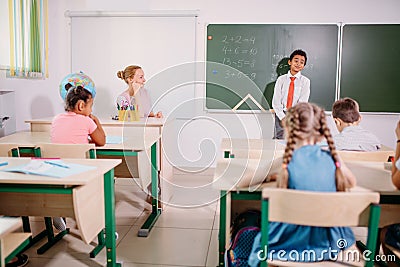Boy solving addition and subtraction on board. schoolboy writing solution of mathematical operation Stock Photo