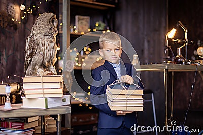 boy with a stack of books comes from the library. Smart schoolboy. Literature lesson. Classroom. Stock Photo