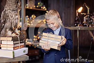 Boy with a stack of books comes from the library. Smart schoolboy. Literature lesson. Classroom. Stock Photo