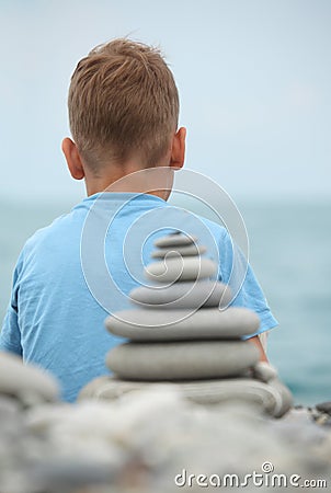 Boy and stone stack, rear view Stock Photo