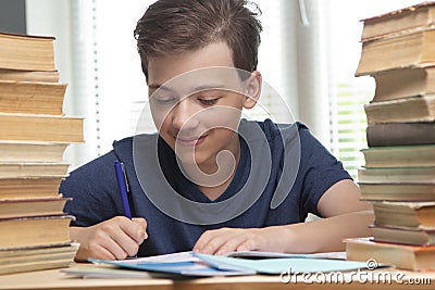 Boy studing at table on blue background and many book Stock Photo