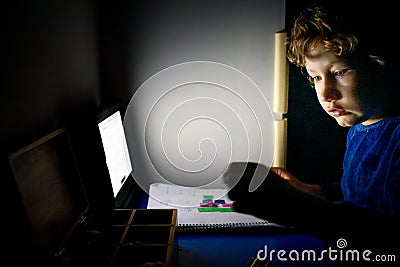 Boy studying mathematics at night alone in his dark room with Montessori material Stock Photo