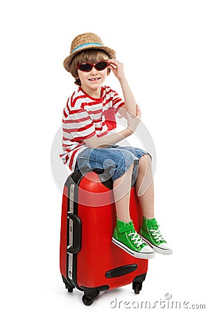 Boy with sunglasses sits on suitcase Stock Photo