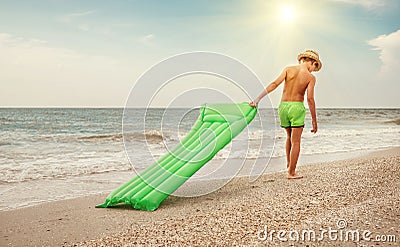 Boy with swimming mattress walks on sand sea beach Stock Photo