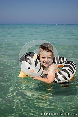 A boy swims, a child with an inflatable lifebuoy in the shape of a zebra. Summer swim. Bathing a child in water. Active Stock Photo