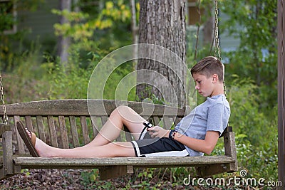Boy in Swing playing or texting on Phone Stock Photo