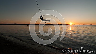 Boy swings from rope over Lake Champlain in Vermont at sunset Stock Photo