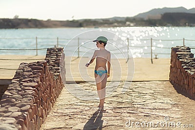 Boy in a swinsuit is standing by the beach Stock Photo