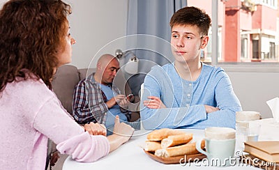 Boy talking to mother on background with indifferent father Stock Photo