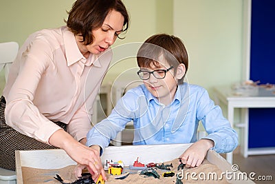 Boy with teacher is sand therapy on table light Stock Photo