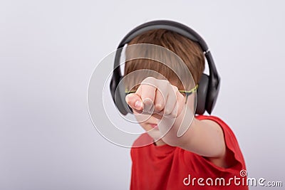 Boy teenager with headphones shows his fist. Child listens to music with headphones Stock Photo