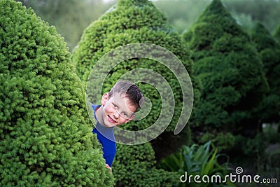 Boy teenager peeking out of a bush Stock Photo