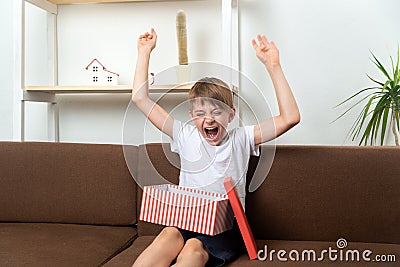 Boy teenager rejoices and has fun having received gift. Happy child with gift Stock Photo