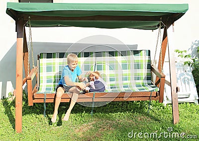 Boy tickling girl on a wooden swing Stock Photo