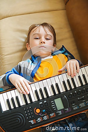 Boy tired of learning to play the synthesizer. Little dreamer want to be a musician Stock Photo