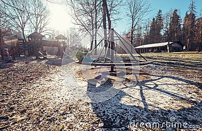 Boy turns on carousel on playground at deep autumn time Stock Photo