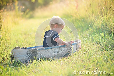 Boy in vintage sailor suit in boat on grass Stock Photo