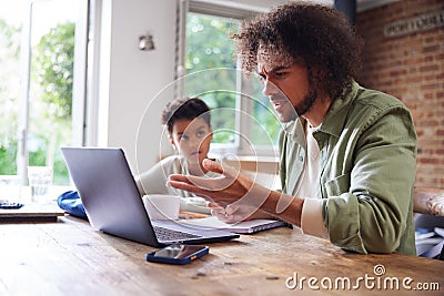 Boy watching father talk during virtual meeting Stock Photo