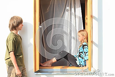 Boy watching girl sitting in the window Stock Photo