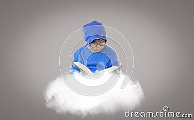 Boy wearing glasses wearing a blue hat, reading book on a cloud that floats in isolated gray background, imaginative concept for Stock Photo