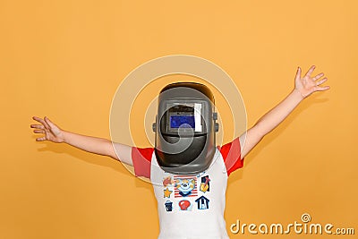 A boy in a welding mask waves his hands in different directions, on a yellow background Stock Photo