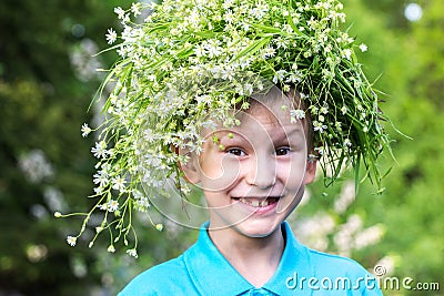 A boy with a wreath of wild flowers. Joy. European style smiling boy in blue polo with a wreath in the garden Stock Photo