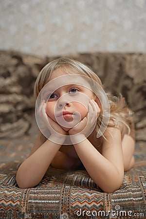 Boy 4 years old is at home lying on the couch and watching TV. Portrait of a blond boy Stock Photo