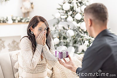 Boyfriend surprises his girlfriend with proposal for Christmas kneeing in front of her Stock Photo