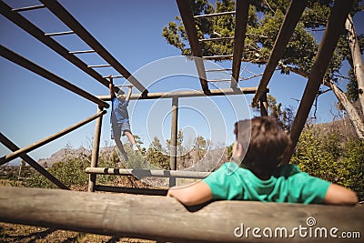 Boys exercising on monkey bar during obstacle course Stock Photo