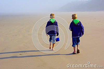Boys explore beach with sand bucket Stock Photo