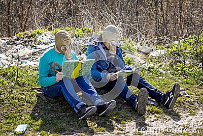 Boys in gas masks in garbage dump read books. Environmental poll Editorial Stock Photo