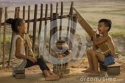 Boys and girls playing folk music with local instruments. Rural children playing with blowing music and laughter. People Thailand Stock Photo