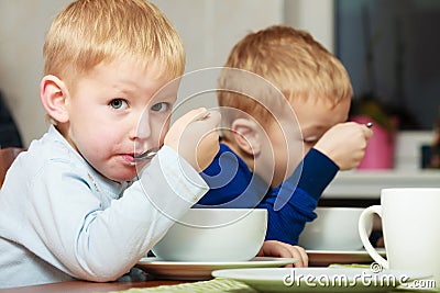 Boys kids children eating corn flakes breakfast meal at the table Stock Photo