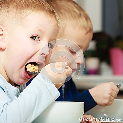 Boys kids children eating corn flakes breakfast meal at the table Stock Photo