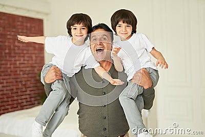 Boys. Portrait of happy latin family, cheerful father holding little twins and smiling at camera while posing, having Stock Photo