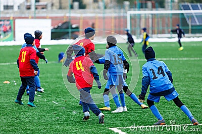 Boys in red and blue sportswear plays soccer on green grass field. Youth football game. Children sport competition, kids plays Editorial Stock Photo