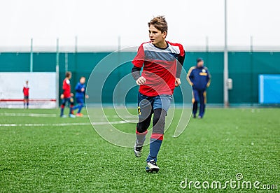 Boys in red white sportswear running on soccer field. Young footballers dribble and kick football ball in game. Training Stock Photo