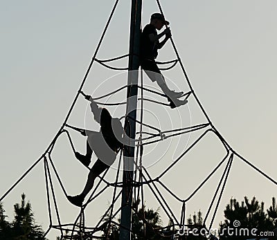 Boys in silhouette on rope and pole adventure climbing frame. Editorial Stock Photo