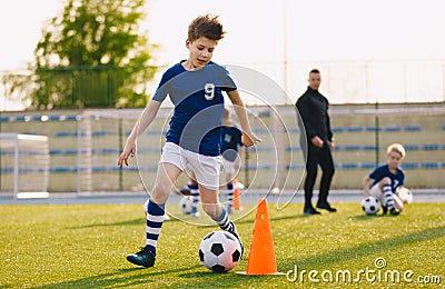 Boys training football dribbling in a field. Kids Running the Ball. Players develop soccer dribbling skills Stock Photo